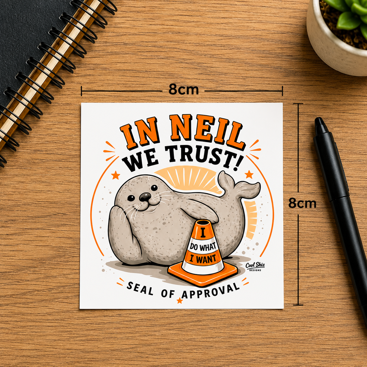 Custom Neil the seal In Neil we trust 8x8cm kiss cut, scratch resistant, waterproof, vinyl sticker shown on a wooden desk. Black dimension lines labeled 8cm indicate the size of the print.