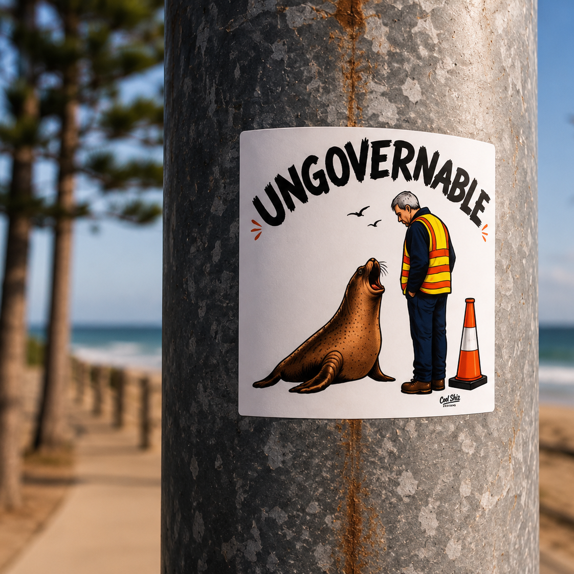 A square white sticker attached to a weathered metal utility pole outdoors. The sticker is a Cool Shiz Neil the seal Ungovernable waterproof, scratch resistant, vinyl sticker.